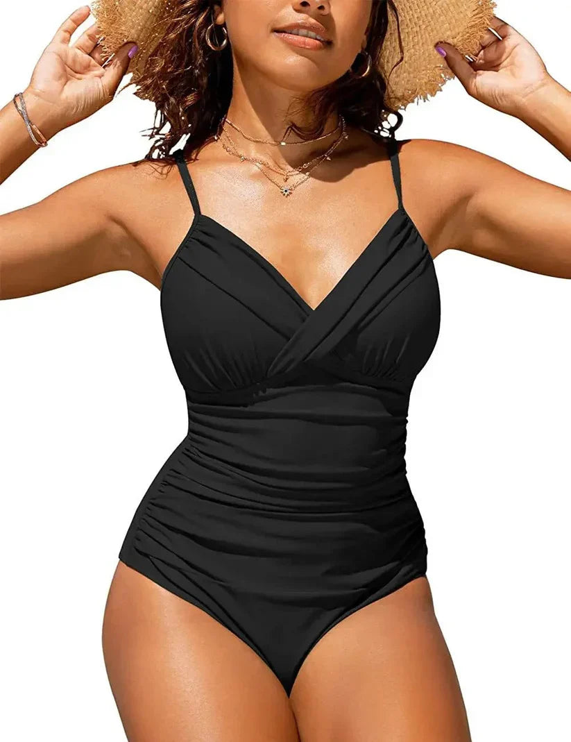 Donna in costume intero nero, spalline sottili, design incrociato, indossa cappello di paglia. Moda mare, abbigliamento estivo, tendenze 2023.