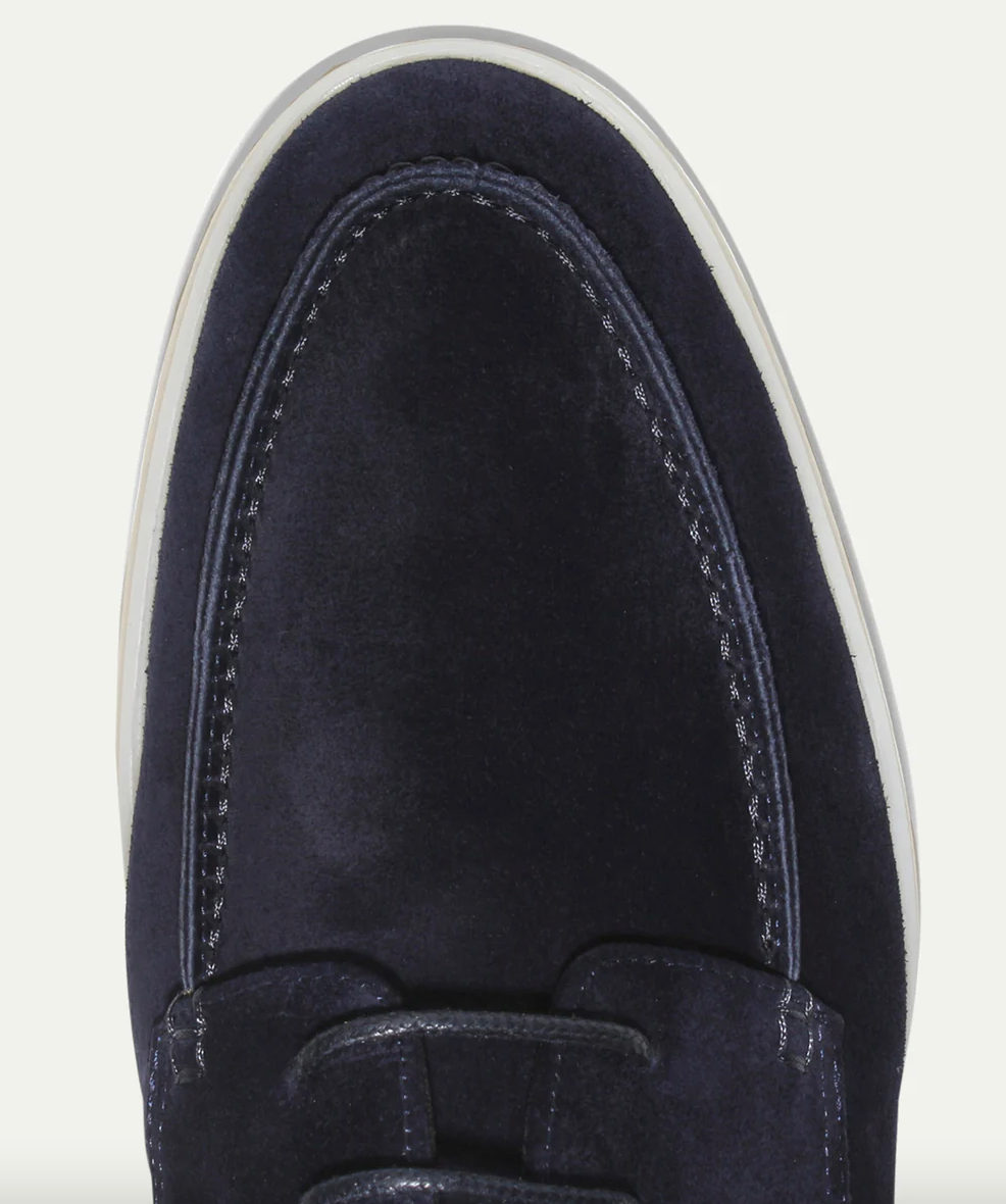 Scarpa da uomo in pelle scamosciata blu navy, vista dall'alto, con cuciture decorative e suola bianca. Elegante e casual, perfetta per ogni occasione.