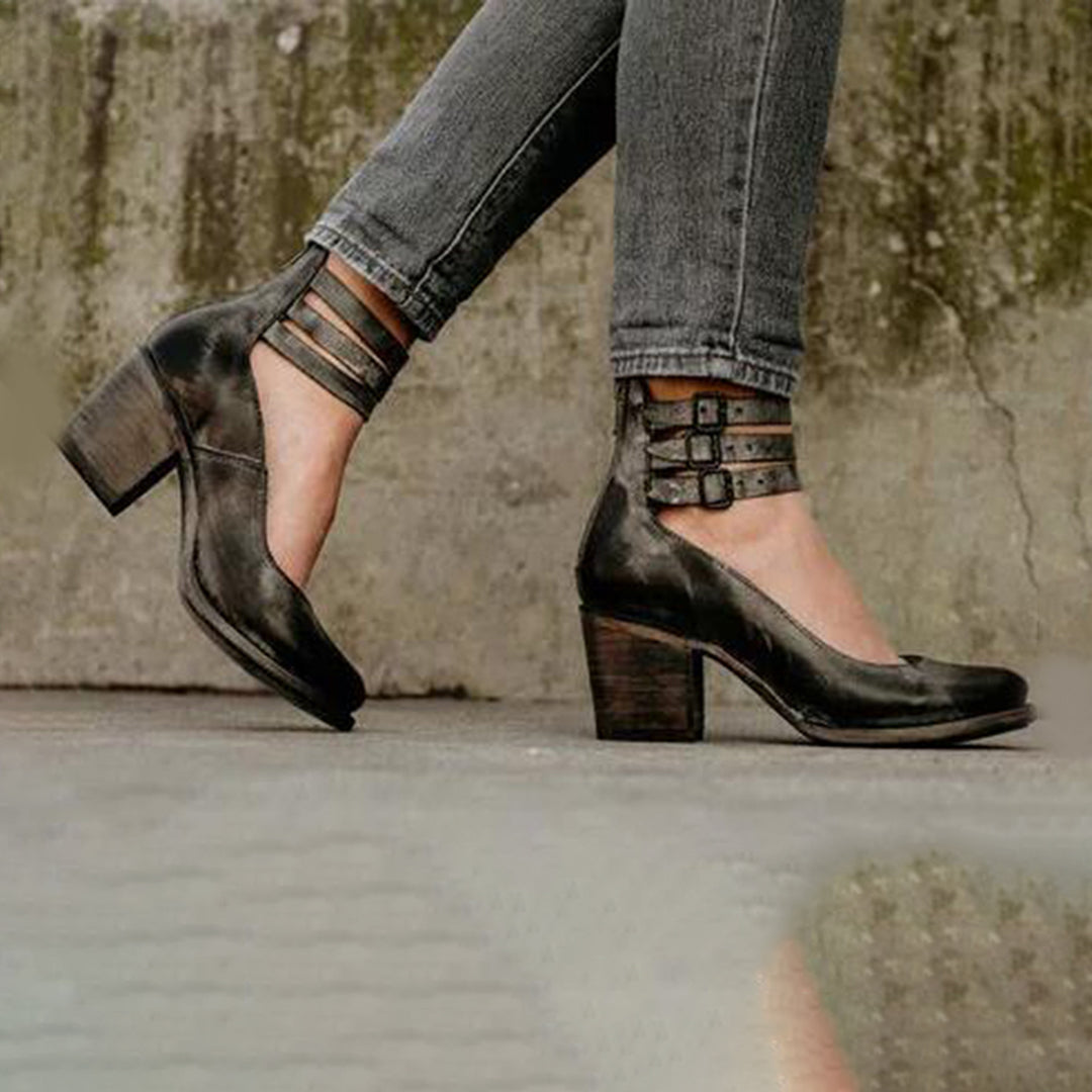 Scarpe donna nere con tacco largo e cinturini multipli, indossate con jeans grigi. Eleganti e versatili, ideali per moda autunno.