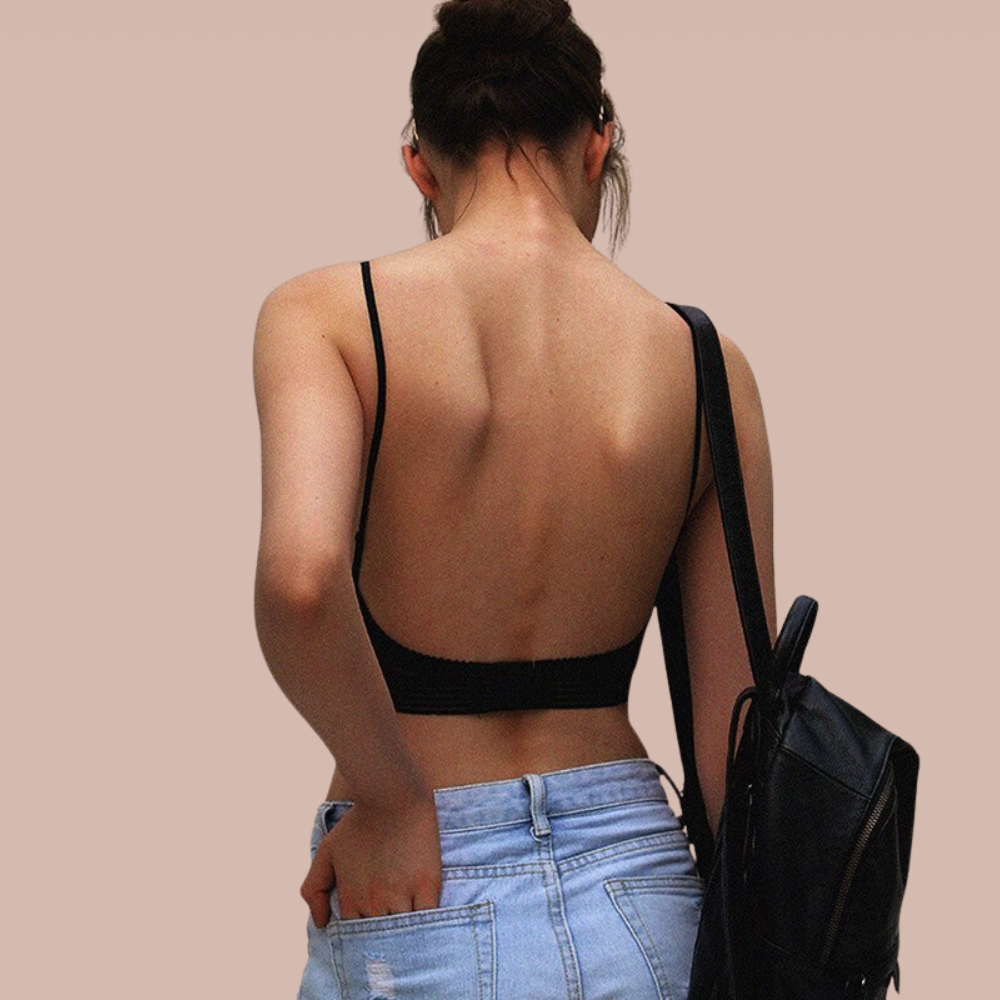 Donna di spalle con top nero senza schiena e jeans chiari, zaino nero. Moda casual estiva, abbigliamento femminile trendy.