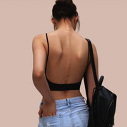 Donna di spalle con top nero senza schiena e jeans chiari, zaino nero. Moda casual estiva, abbigliamento femminile trendy.