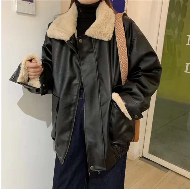 Giacca in pelle nera con fodera in pelliccia sintetica bianca, indossata su maglione nero e jeans. Moda invernale, abbigliamento casual elegante.
