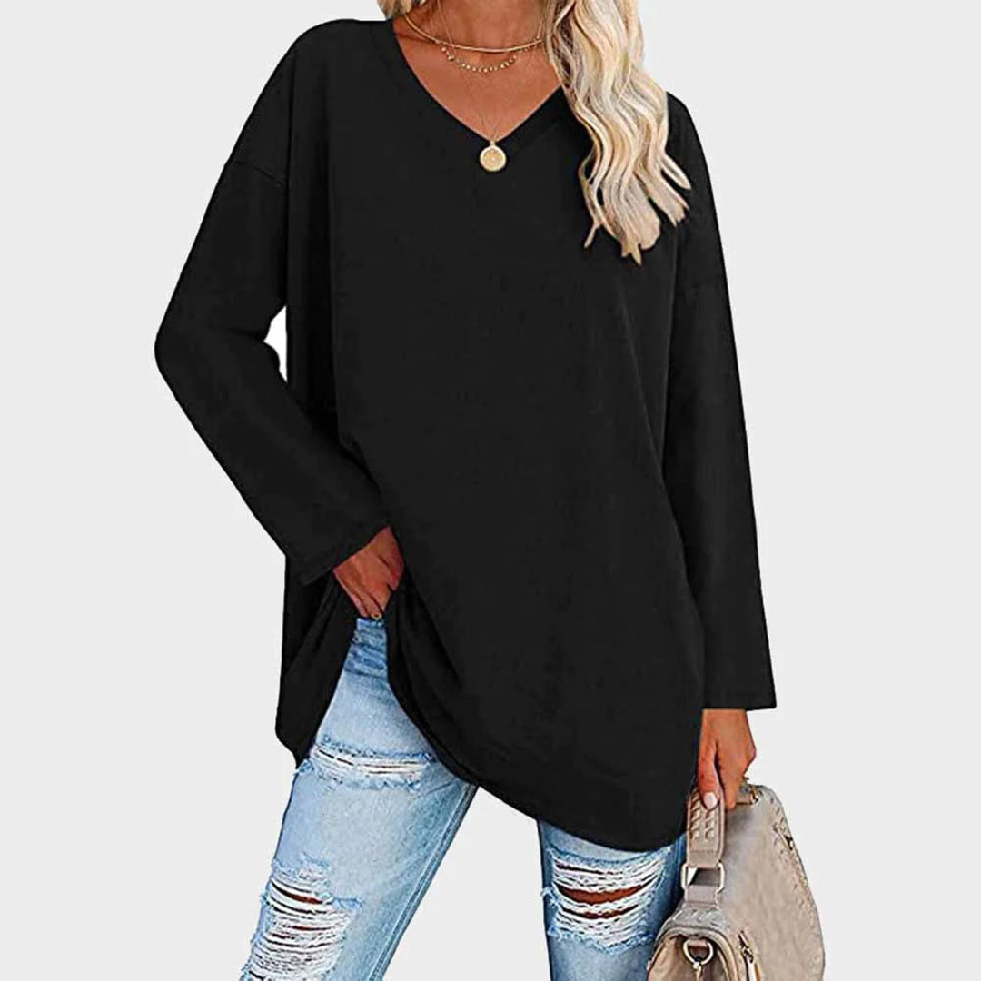 Donna con maglia nera oversize, jeans strappati e borsa beige. Moda casual femminile, abbigliamento autunnale, stile urbano chic.