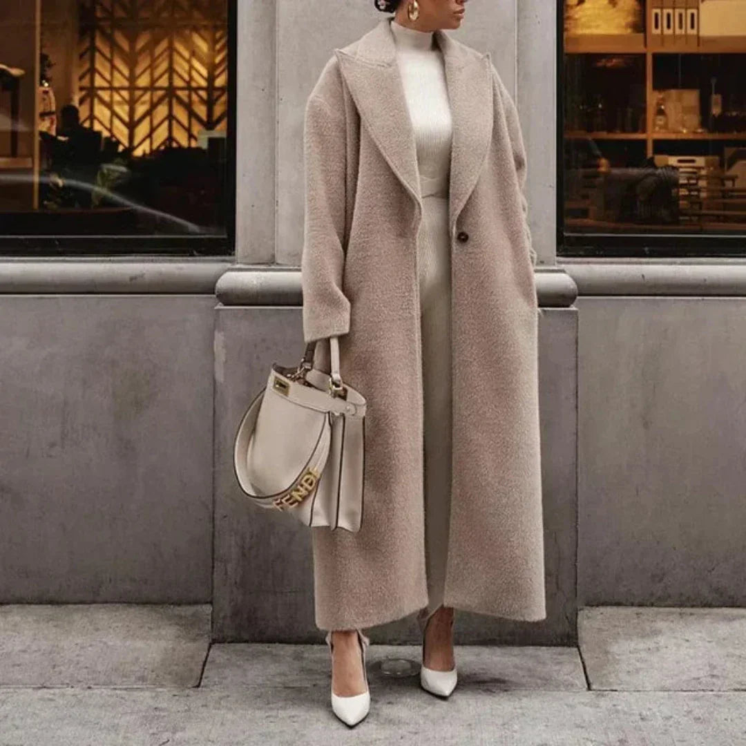 Cappotto lungo beige elegante, abbinato a borsa Fendi e scarpe bianche, indossato da donna in città. Moda autunnale, stile sofisticato.