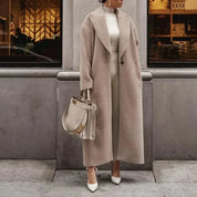 Cappotto lungo beige elegante, abbinato a borsa Fendi e scarpe bianche, indossato da donna in città. Moda autunnale, stile sofisticato.