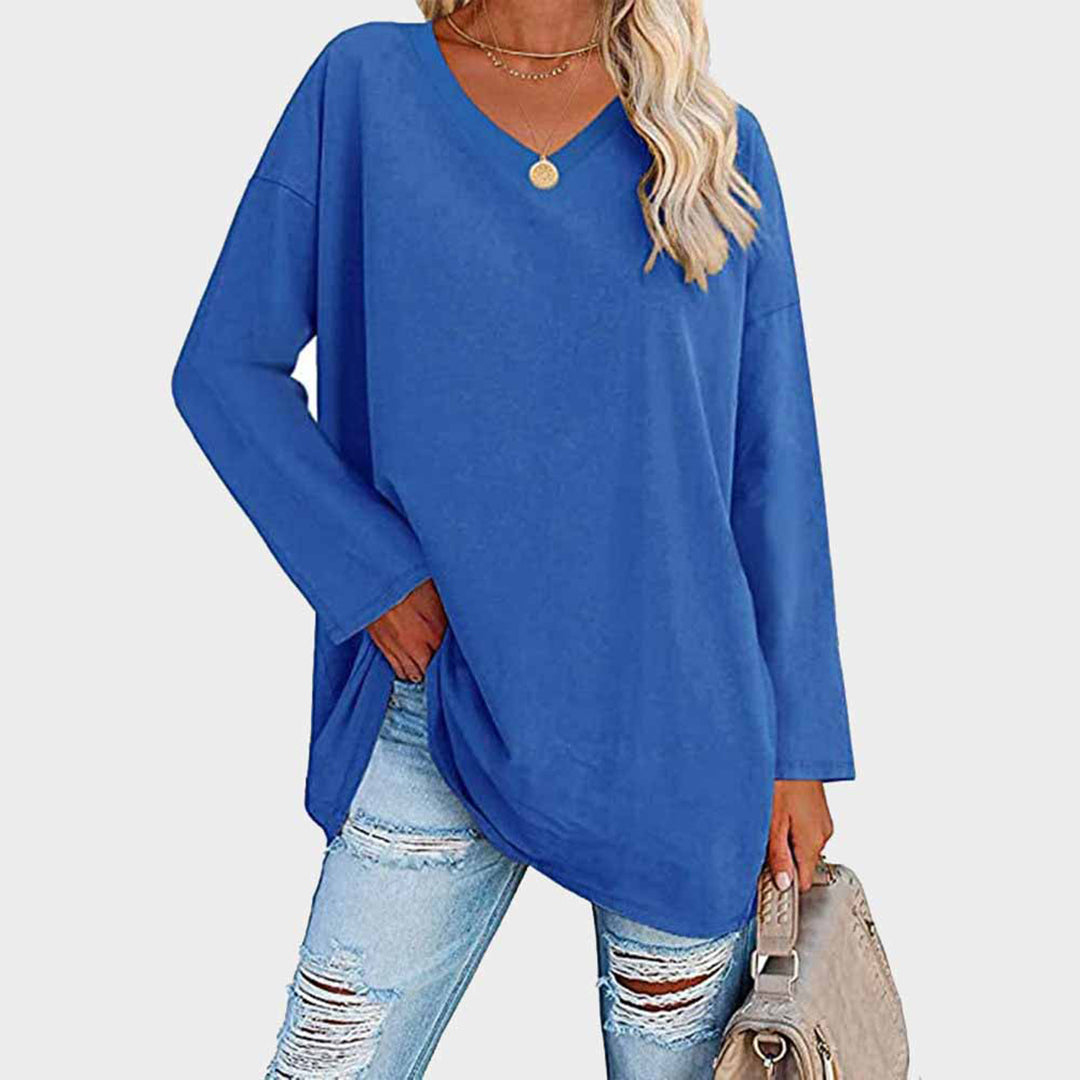 Donna con maglia oversize blu, jeans strappati, borsa beige. Moda casual femminile, abbigliamento autunnale, stile urbano.