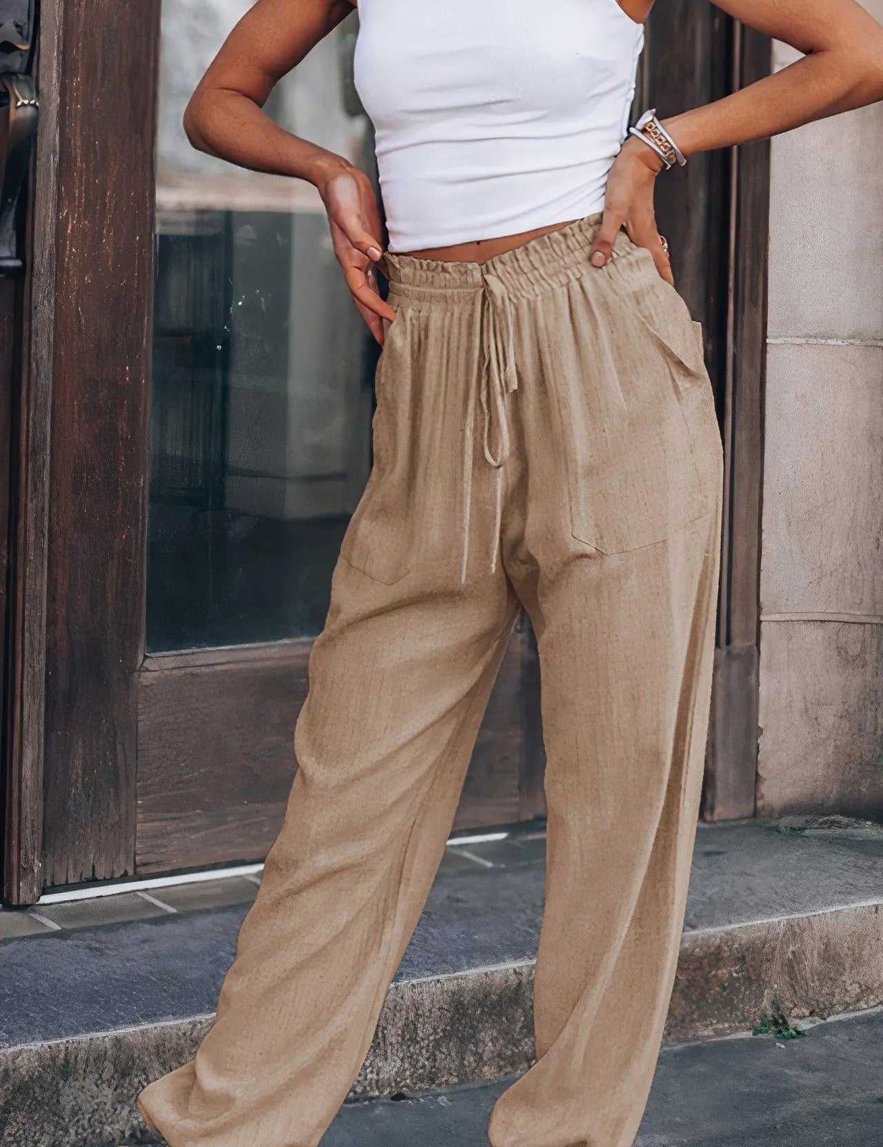 Pantaloni larghi beige da donna, stile casual, con elastico in vita e tasche, abbinati a top bianco. Look estivo alla moda per passeggiate urbane.