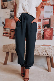 Donna in pantaloni neri larghi e camicia bianca, posa in un ambiente moderno con poster artistici. Moda casual, abbigliamento femminile elegante.