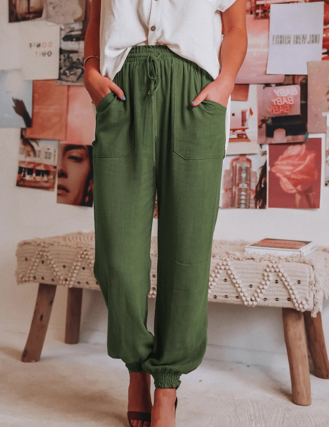 Donna in camicia bianca e pantaloni verdi, posa casual in interni boho chic. Moda femminile estiva, abbigliamento comodo ed elegante.