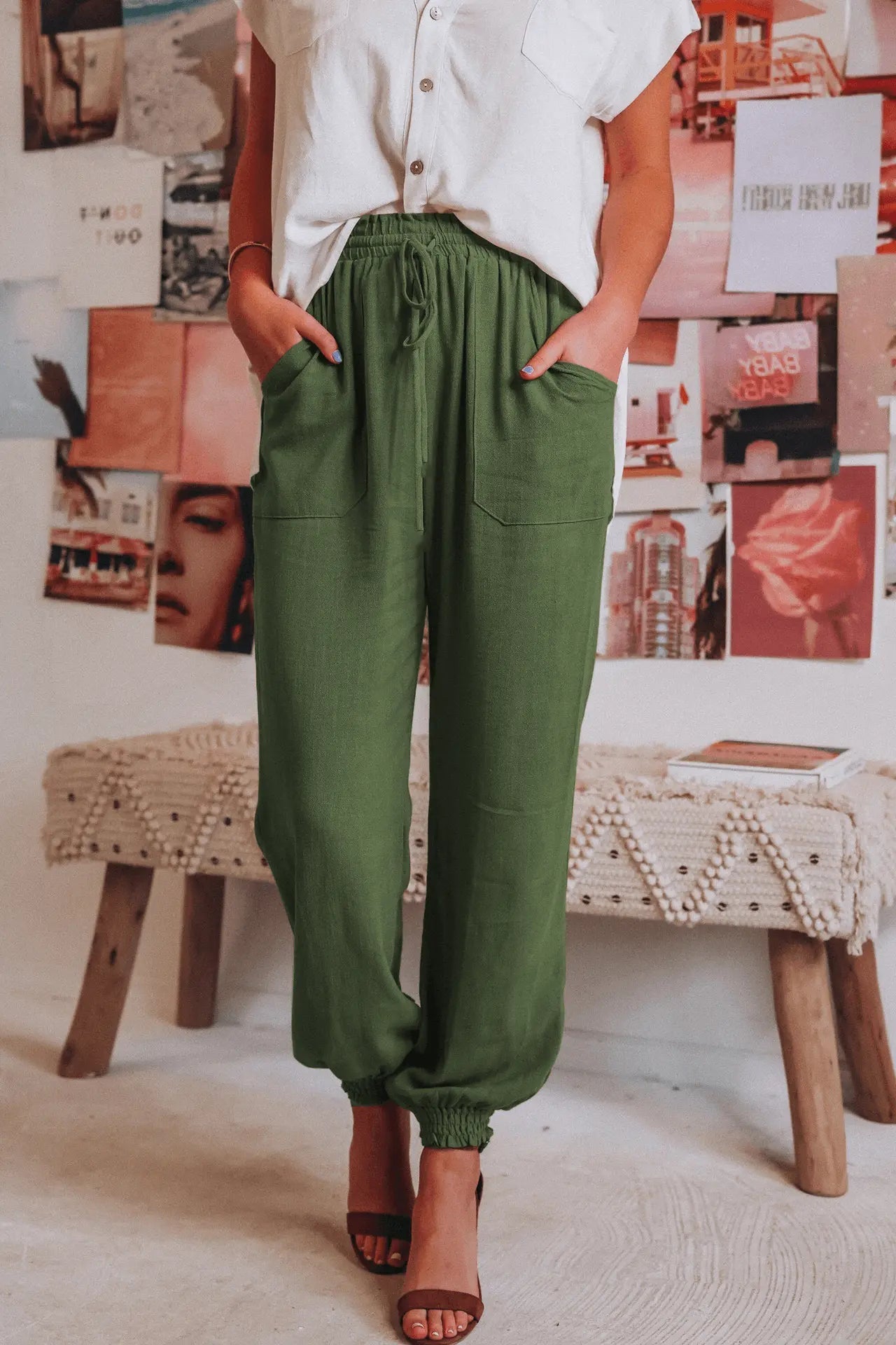 Donna in camicia bianca e pantaloni verdi, posa casual in interni boho chic. Moda femminile estiva, abbigliamento comodo ed elegante.
