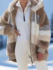 Giacca in pelliccia sintetica a righe beige e bianche, con cappuccio e zip, indossata su neve. Moda invernale, abbigliamento caldo e trendy.