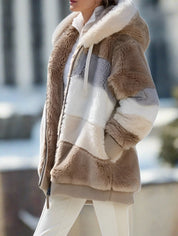 Giacca in pelliccia sintetica a righe beige e bianche con cappuccio, indossata da una donna. Moda invernale elegante e calda.