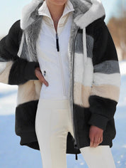 Giacca invernale donna in pelliccia sintetica a righe multicolore, con cappuccio, zip frontale, indossata su neve. Elegante e calda per l'inverno.