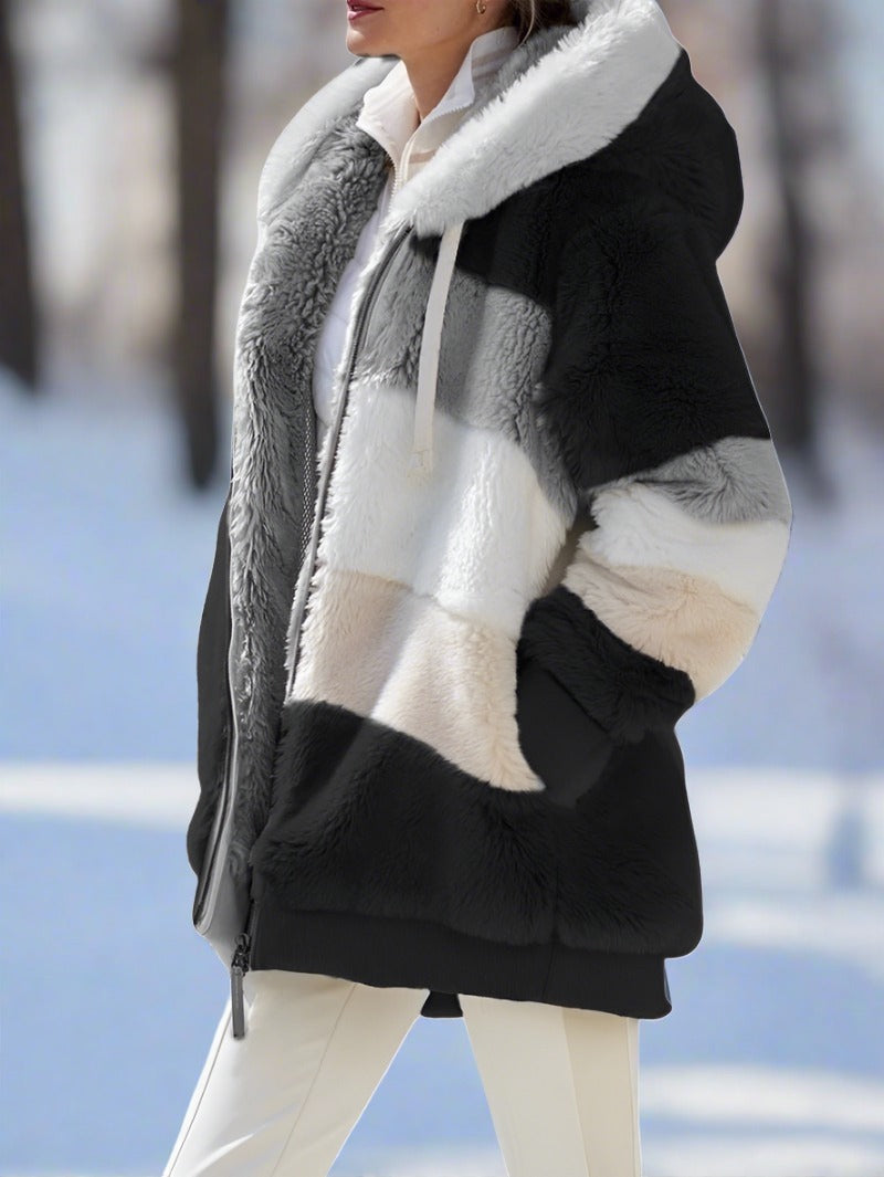 Giacca invernale donna in pelliccia sintetica a blocchi di colore, cappuccio, chiusura zip, sfondo innevato. Elegante e calda per l'inverno.