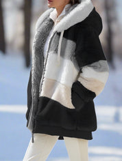Giacca invernale donna in pelliccia sintetica a blocchi di colore, cappuccio, chiusura zip, sfondo innevato. Elegante e calda per l'inverno.