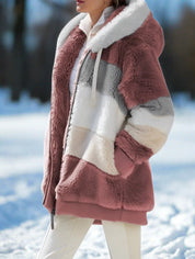 Giacca in pelliccia sintetica a righe rosa, bianco e grigio con cappuccio, indossata all'aperto su neve. Moda invernale donna, abbigliamento caldo.