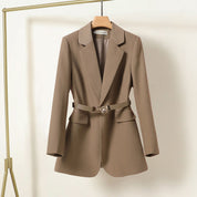 Blazer donna marrone con cintura, elegante e moderno, appeso su gruccia. Giacca sartoriale, ideale per abbigliamento formale e casual chic.