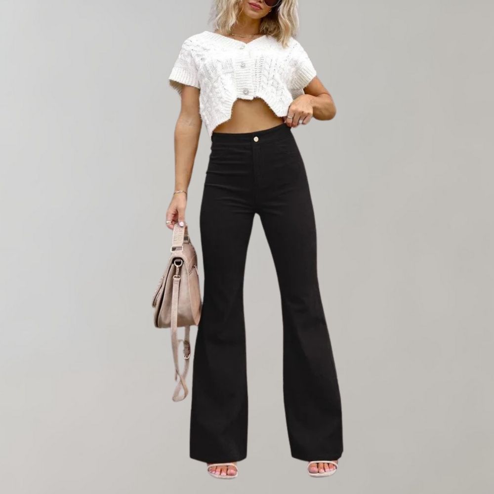 Donna con pantaloni a zampa neri e top bianco corto, borsa beige, sandali rosa. Moda casual elegante, abbigliamento femminile trendy.