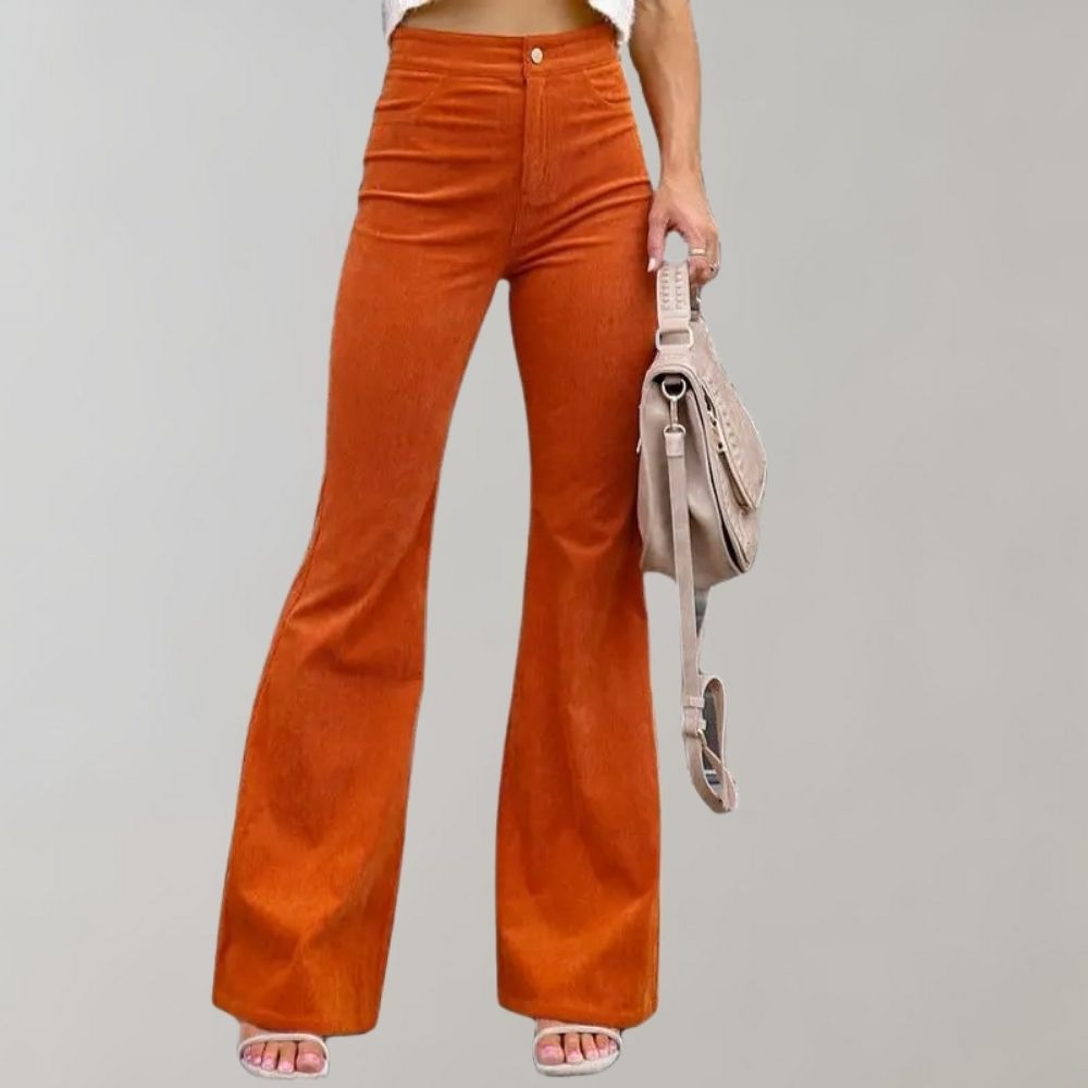 Pantaloni a zampa arancioni in velluto a coste, donna, con borsa beige. Moda autunnale, abbigliamento casual elegante.