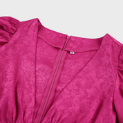 Vestito rosa fucsia in raso con motivo floreale, scollo a V e maniche a sbuffo. Chiusura con zip posteriore. Taglia M. Elegante e alla moda.