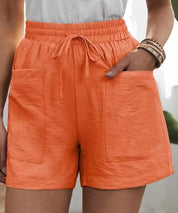 Shorts arancioni da donna con tasche frontali, vita alta elasticizzata e laccio. Stile casual estivo, tessuto leggero.