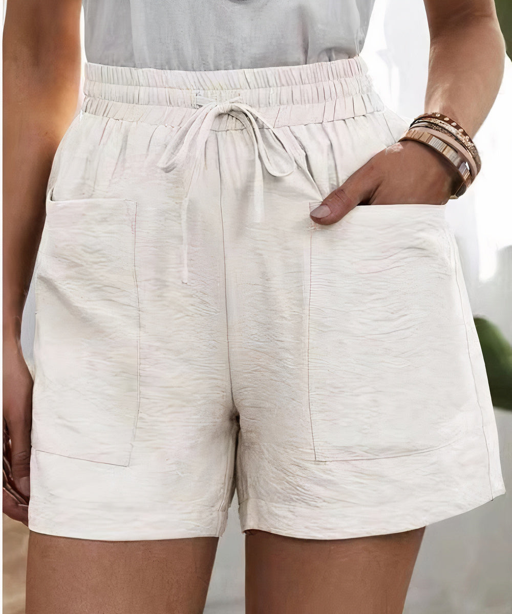 Shorts bianchi da donna in tessuto leggero, con tasche frontali e vita elasticizzata con laccio. Ideali per l'estate e il tempo libero.