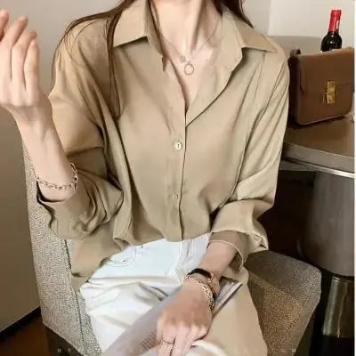 Camicia beige da donna elegante, maniche lunghe, abbinata a pantaloni bianchi. Look casual chic, perfetto per moda autunnale.