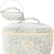 Borsa cosmetica beige con stampa floreale blu, manico superiore e chiusura a zip. Ideale per viaggi, organizzazione trucco e accessori.
