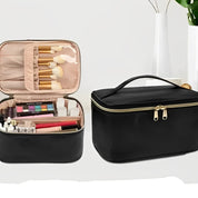 Due beauty case neri con cerniera, uno aperto con pennelli trucco, ombretti e rossetti, l'altro chiuso; eleganti e pratici per cosmetici.