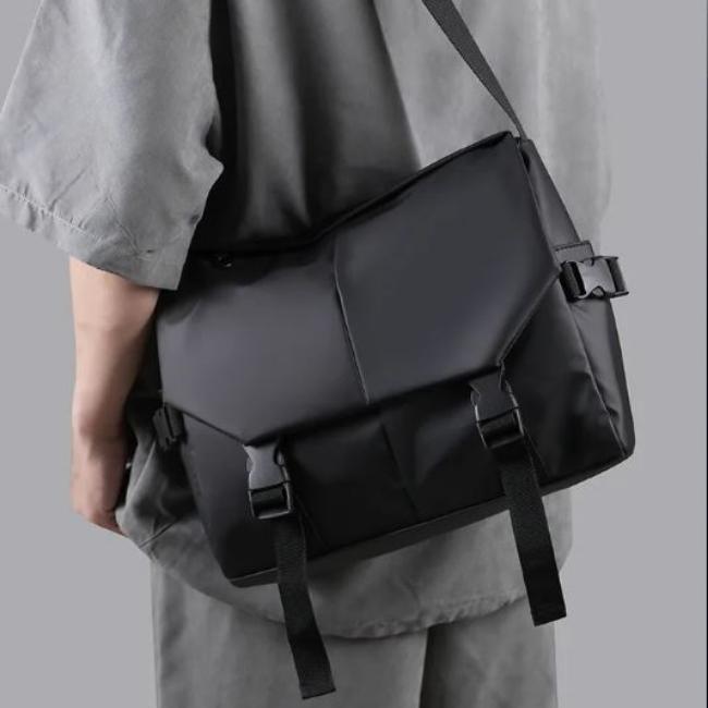 Borsa a tracolla nera unisex, design moderno, materiale impermeabile, chiusure a fibbia, ideale per lavoro e viaggio.