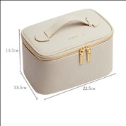 Astuccio cosmetico beige in pelle sintetica con cerniera dorata, manico superiore, dimensioni 22,5x13,5x13,5 cm. Elegante e pratico per viaggi.