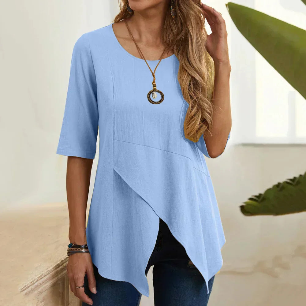 Blusa donna azzurra a maniche corte, design asimmetrico, scollo rotondo, abbinata a jeans. Moda casual estiva, elegante e confortevole.