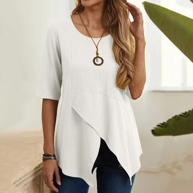 Maglietta bianca asimmetrica da donna, maniche corte, con collana pendente, abbinata a jeans. Moda casual estiva, abbigliamento femminile elegante.