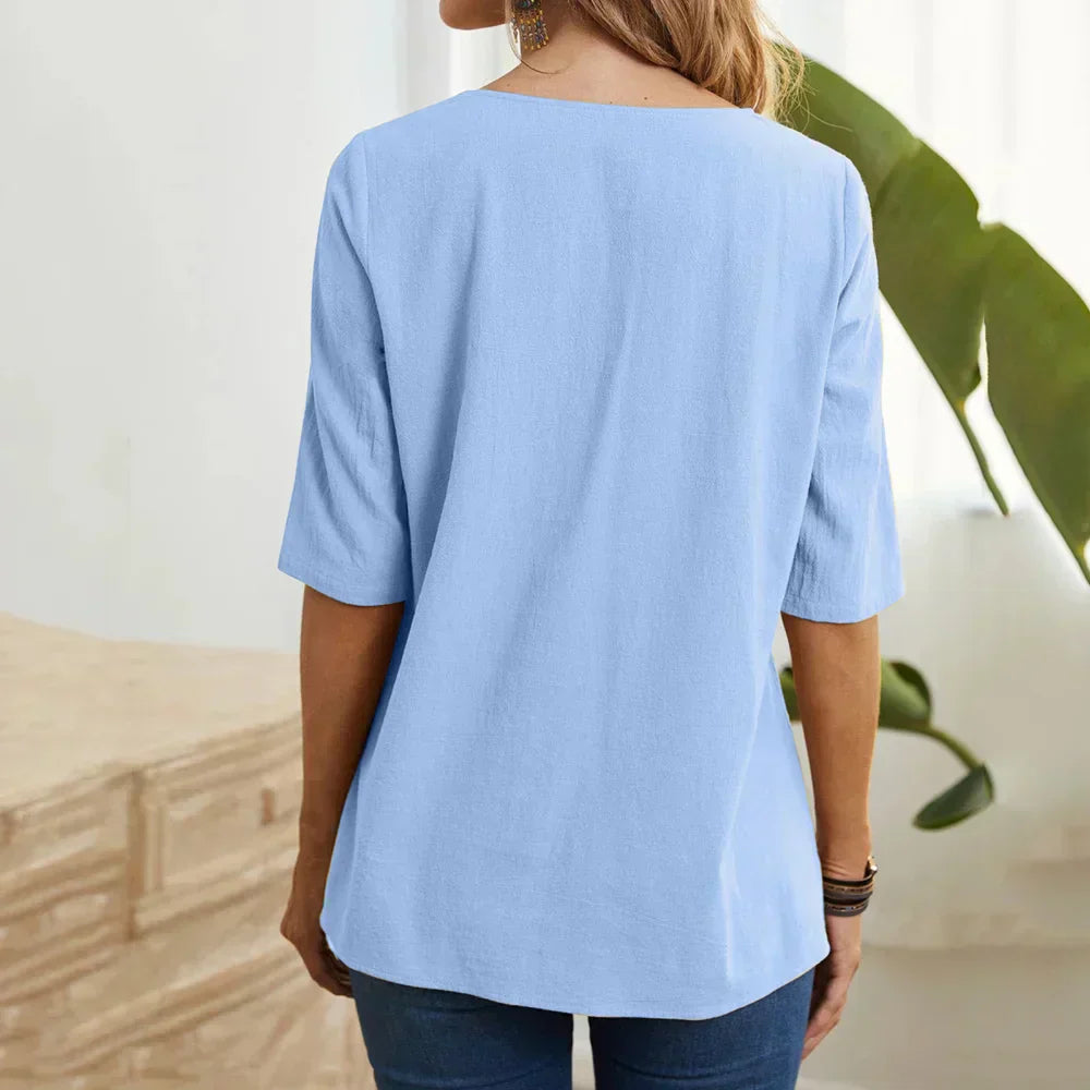 Donna con maglietta azzurra a maniche corte, vista posteriore. Abbigliamento casual estivo, tessuto leggero, ideale per look quotidiani.
