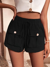 Shorts neri da donna con tasche frontali e bottoni, abbinati a un top bianco senza maniche. Stile casual estivo, moda femminile trendy.