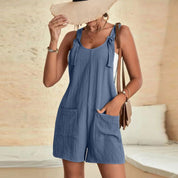 Donna con cappello di paglia indossa una tuta corta blu con tasche, perfetta per l'estate. Moda casual femminile, abbigliamento estivo elegante.