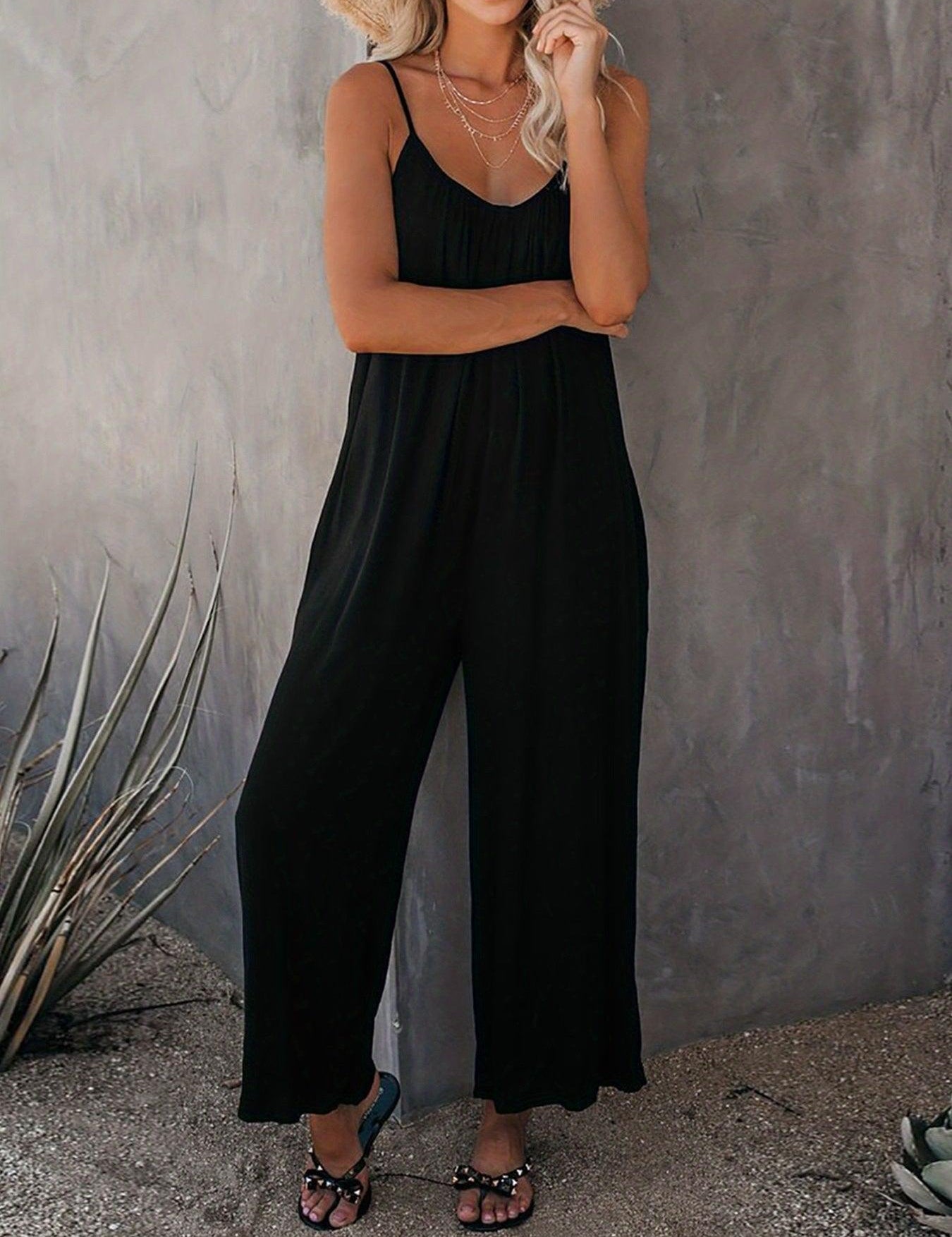 Donna con tuta nera estiva, sandali eleganti e cappello di paglia. Moda casual chic, abbigliamento estivo femminile, outfit trendy per il tempo libero.