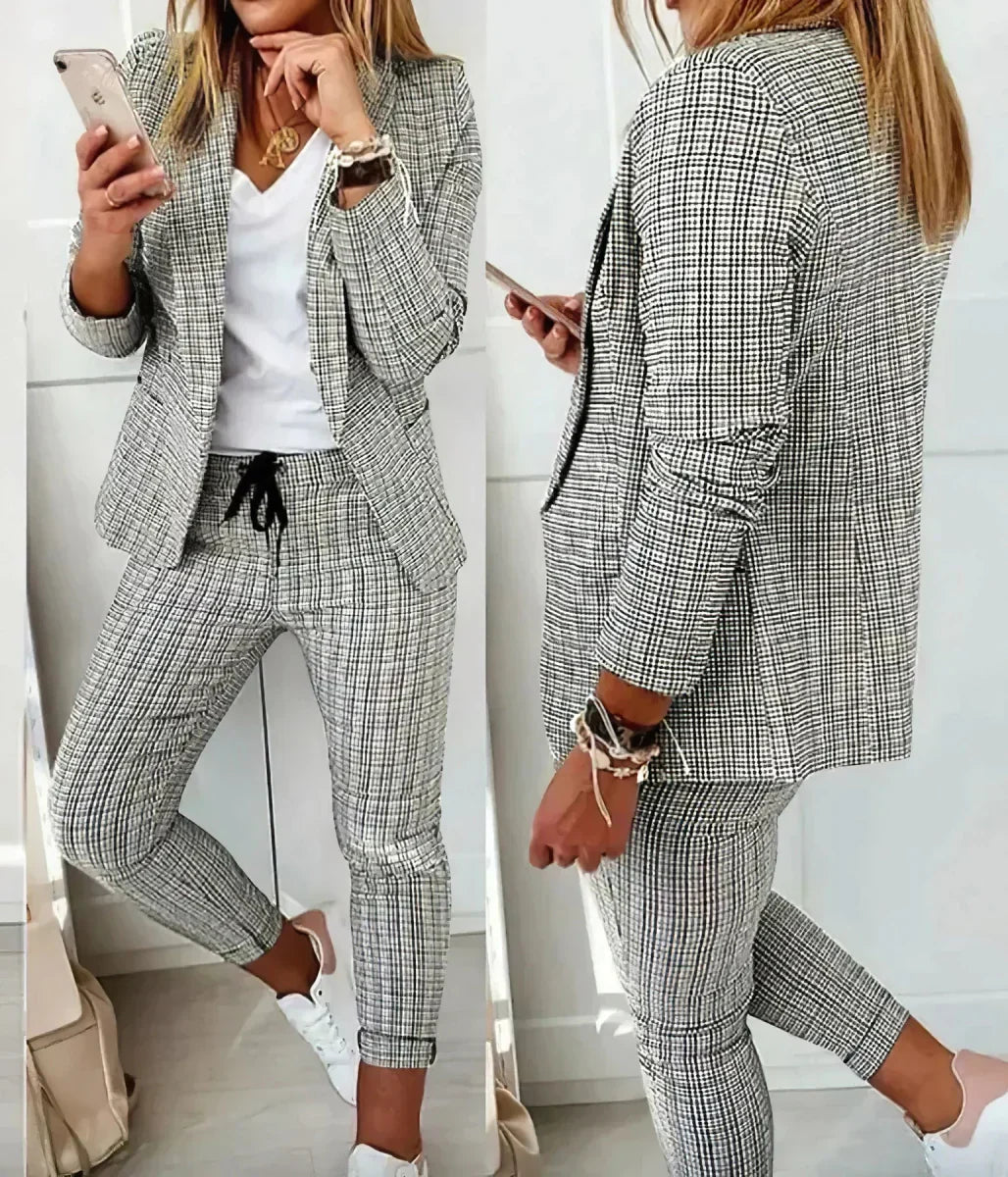 Donna in completo giacca e pantaloni a quadri bianchi e neri, con t-shirt bianca e sneakers. Moda casual elegante, outfit femminile moderno.
