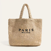 Borsa shopper in paglia intrecciata con manici, scritta "Paris Milano" in nero. Elegante e spaziosa, perfetta per lo shopping estivo.