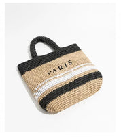 Borsa a mano in paglia intrecciata beige e nera con scritta "Paris", design estivo, moda donna, accessorio casual chic, shopping bag elegante.