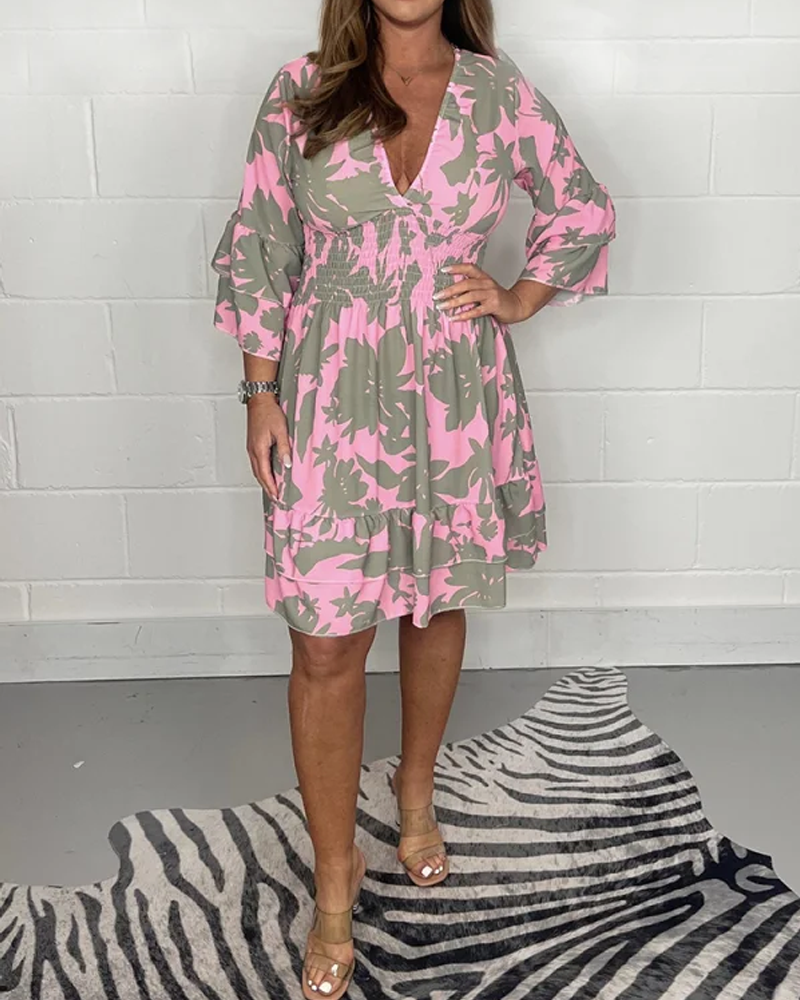 Abito donna floreale rosa e verde, maniche a tre quarti, scollo a V, lunghezza al ginocchio, indossato con sandali beige su tappeto zebrato.