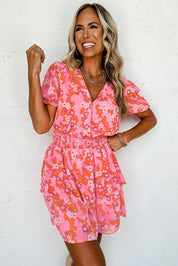 Donna sorridente in abito estivo rosa con stampa floreale arancione, maniche corte e scollo a V. Moda femminile, abbigliamento casual elegante.