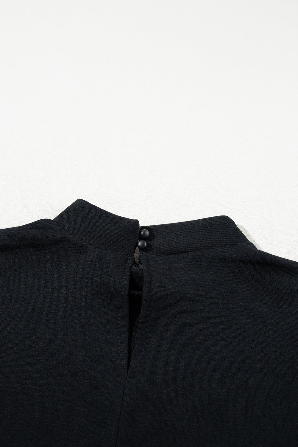 Blusa nera con colletto alto e chiusura a bottone sul retro, elegante e minimalista, perfetta per look formali e casual. Tessuto morbido e confortevole.
