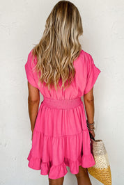 Donna con abito rosa a balze, capelli biondi ondulati, borsa di paglia. Moda estiva, abbigliamento casual femminile.