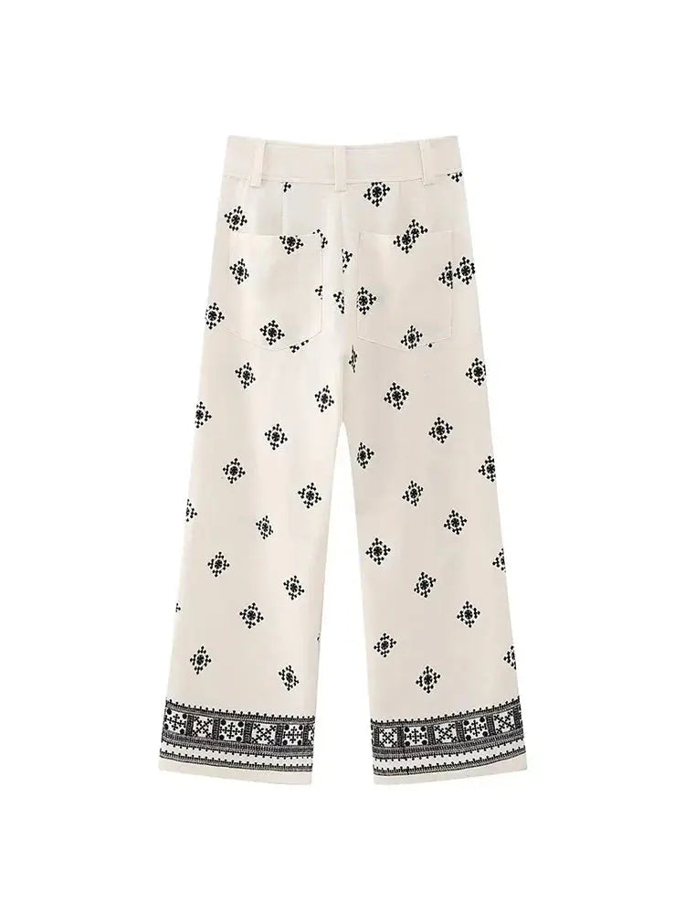 Pantaloni bianchi donna con motivo geometrico nero, taglio ampio, tasche posteriori, orlo decorato. Stile casual elegante.