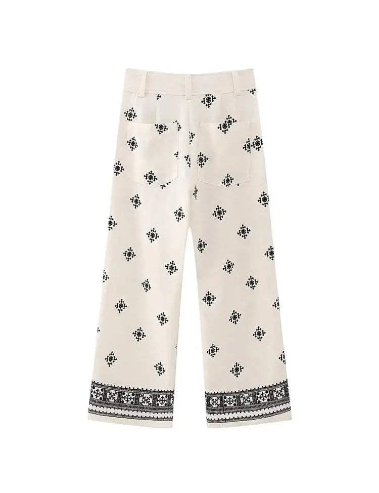 Pantaloni bianchi donna con motivo geometrico nero, taglio ampio, tasche posteriori, orlo decorato. Stile casual elegante.