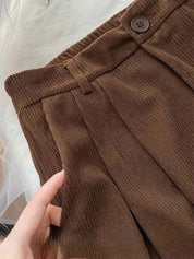 Pantaloni marroni a vita alta in tessuto a coste, con cintura elastica e bottone. Design elegante e versatile per moda autunnale.