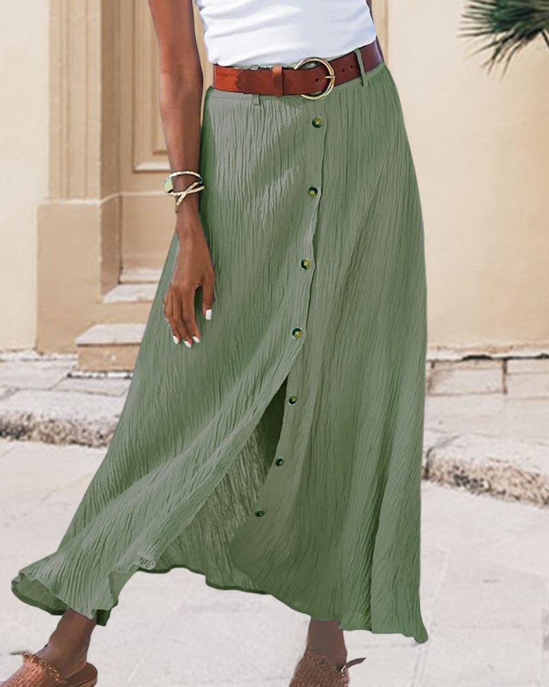 Gonna lunga verde con bottoni, cintura marrone, indossata con top bianco. Moda estiva donna, abbigliamento casual elegante.
