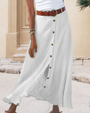 Gonna lunga bianca a bottoni, tessuto plissettato, cintura marrone, look estivo casual, moda donna, abbigliamento elegante, outfit urbano.