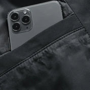 iPhone nero con tripla fotocamera in tasca giacca nera, smartphone Apple, design elegante, tecnologia avanzata, accessorio moda.